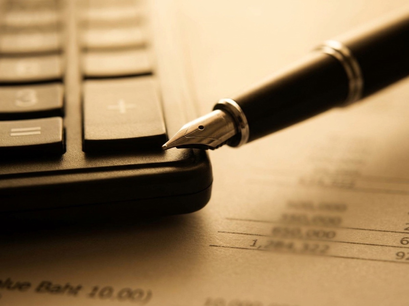 Fountain pen nib resting on a calculator above a printed sheet of financial figures