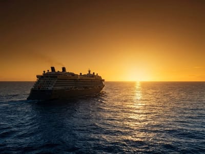 A large cruise ship navigates open ocean water toward a bright setting sun on the horizon.